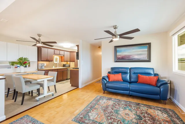 a living room with furniture kitchen view and a wooden floor