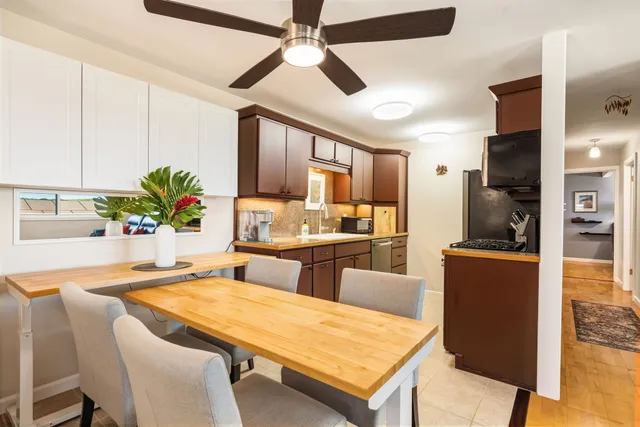 a kitchen with stainless steel appliances kitchen island granite countertop a stove a refrigerator a sink a dining table and chairs with wooden floor