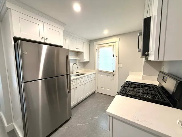 a kitchen with a refrigerator a stove a sink dishwasher and white cabinets with wooden floor