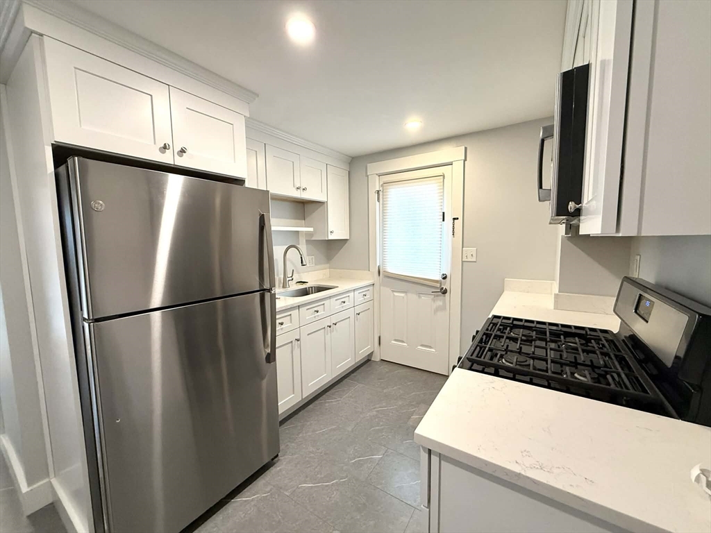a kitchen with a refrigerator a stove a sink dishwasher and white cabinets with wooden floor