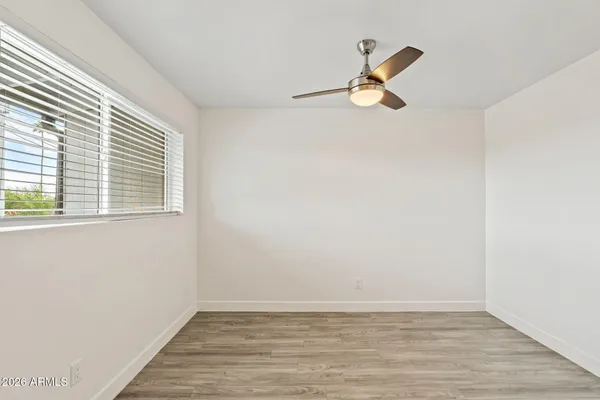 a view of empty room with wooden floor and fan