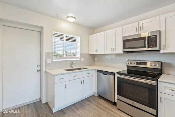 a kitchen with cabinets stainless steel appliances a sink and a window