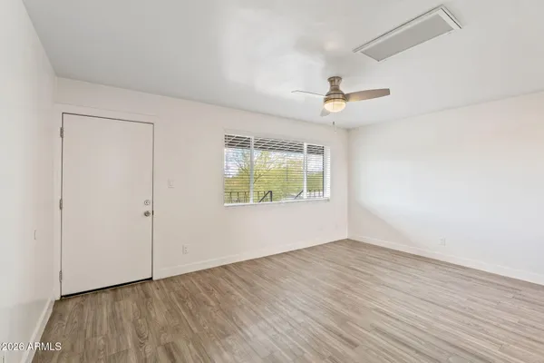 an empty room with wooden floor chandelier fan and windows