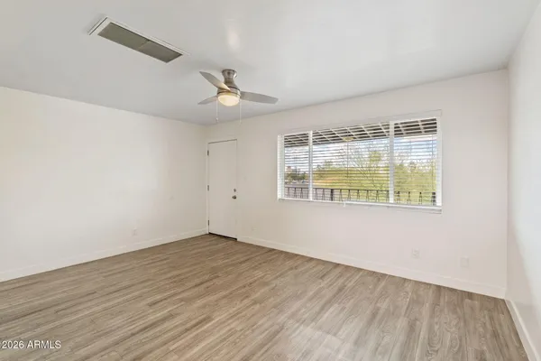 an empty room with wooden floor and windows