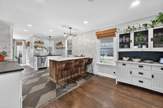 a kitchen with kitchen island a stove a table and chairs in it