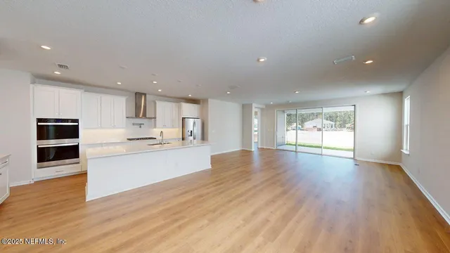a large kitchen with stainless steel appliances granite countertop a large counter top and a wooden floor