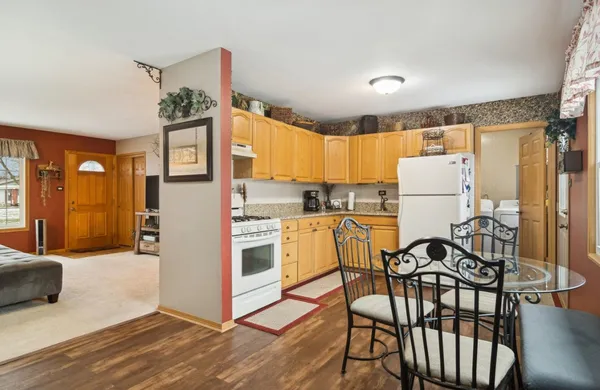 a kitchen with stainless steel appliances a refrigerator a stove top oven and a dining table with wooden floor