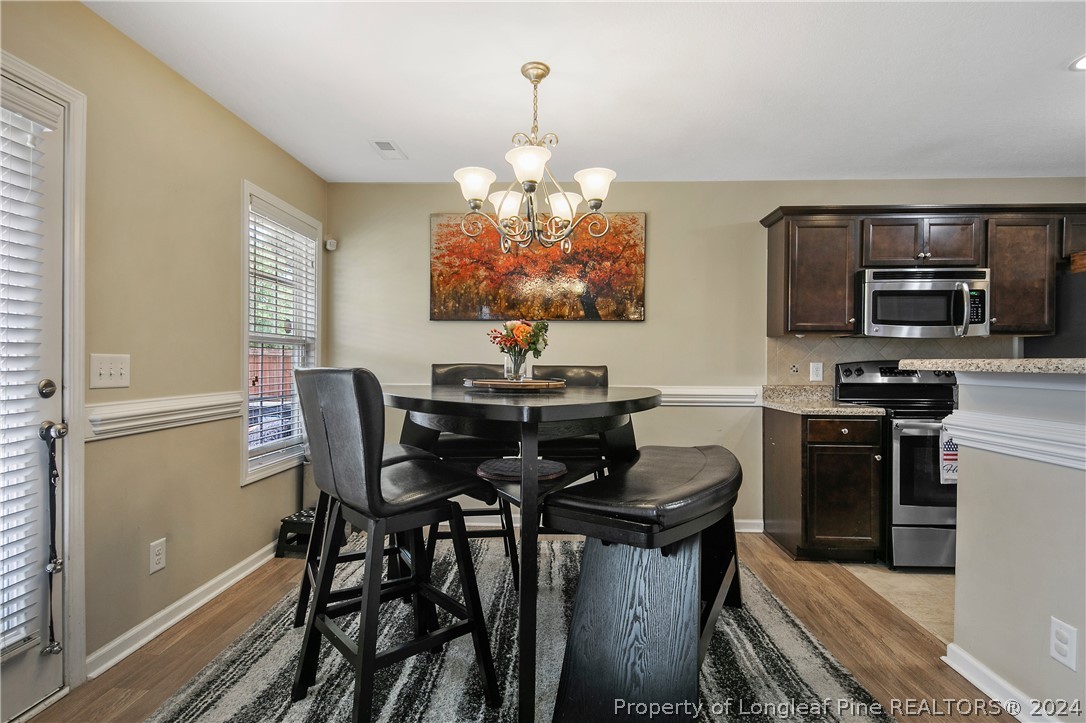 Undisclosed Address Hope Mills, NC 28348 - Photo 13 of 46 a kitchen with stainless steel appliances granite countertop a stove top oven a refrigerator a dining table and chairs with wooden floor