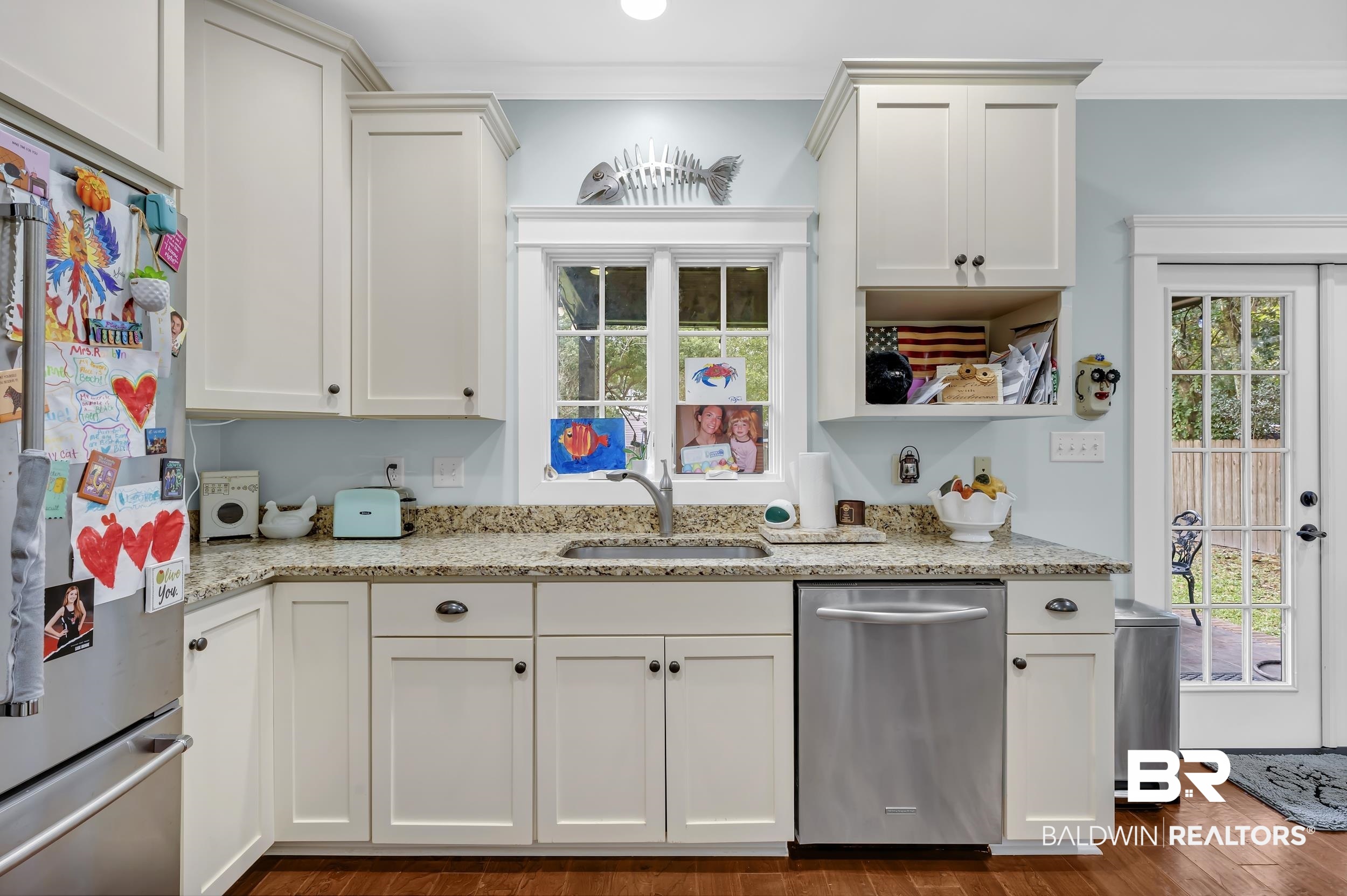 7 Bienville Avenue Mobile, AL 36606 - Photo 17 of 32 Kitchen featuring appliances with stainless steel finishes, light stone countertops, dark wood-style floors, ornamental molding, and white cabinetry