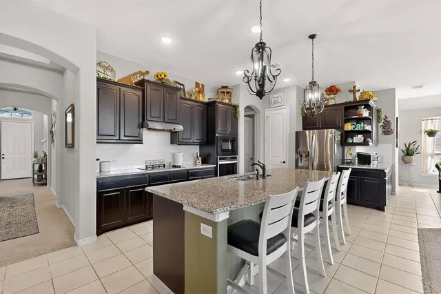 a kitchen with kitchen island granite countertop a sink a center island and stainless steel appliances