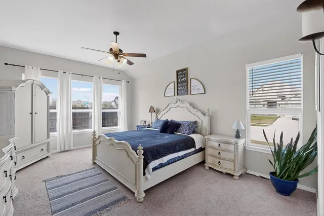 a spacious bedroom with a bed table flowerpot and window
