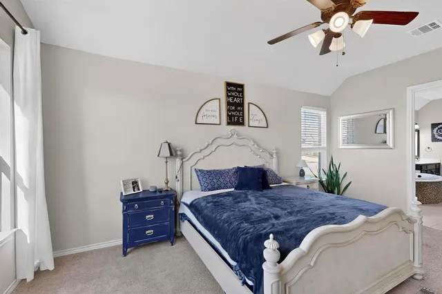 a bedroom with a large bed and a chandelier fan