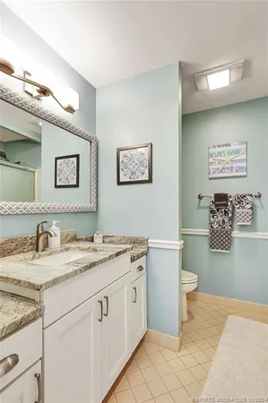 a bathroom with a granite countertop double vanity sink and mirror
