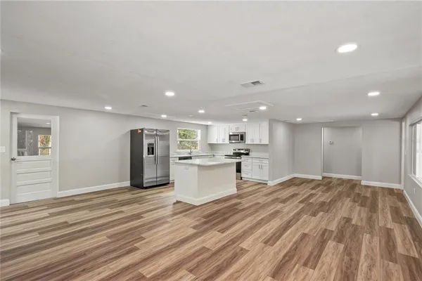 a view of kitchen with kitchen island wooden floor center island and stainless steel appliances