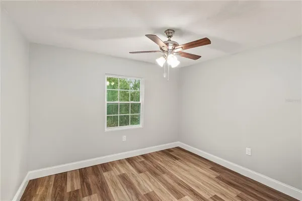 an empty room with a window and a fan