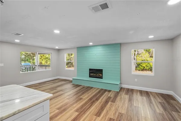 an empty room with windows and fireplace