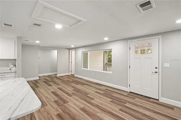 a view of an empty room with window and wooden floor