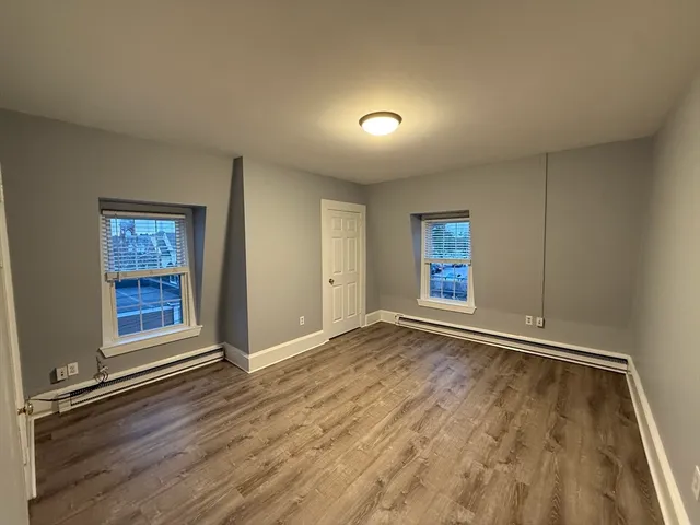 an empty room with wooden floor & closet and windows