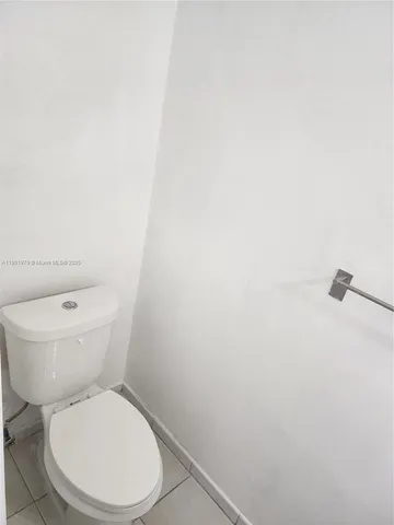 a white toilet sitting next to a white wall