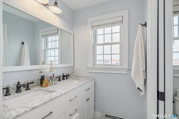 a bathroom with a granite countertop sink and a window