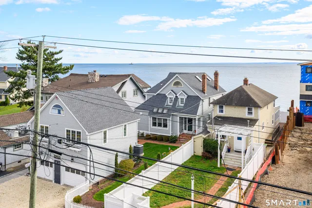 a view of a white house with a big yard and potted plants