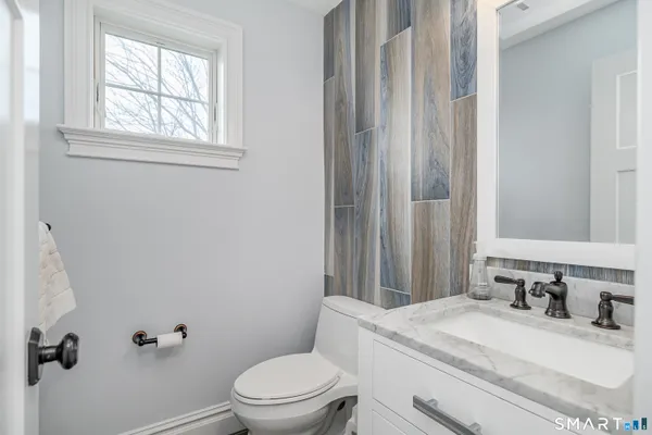 a bathroom with a granite countertop sink toilet and mirror