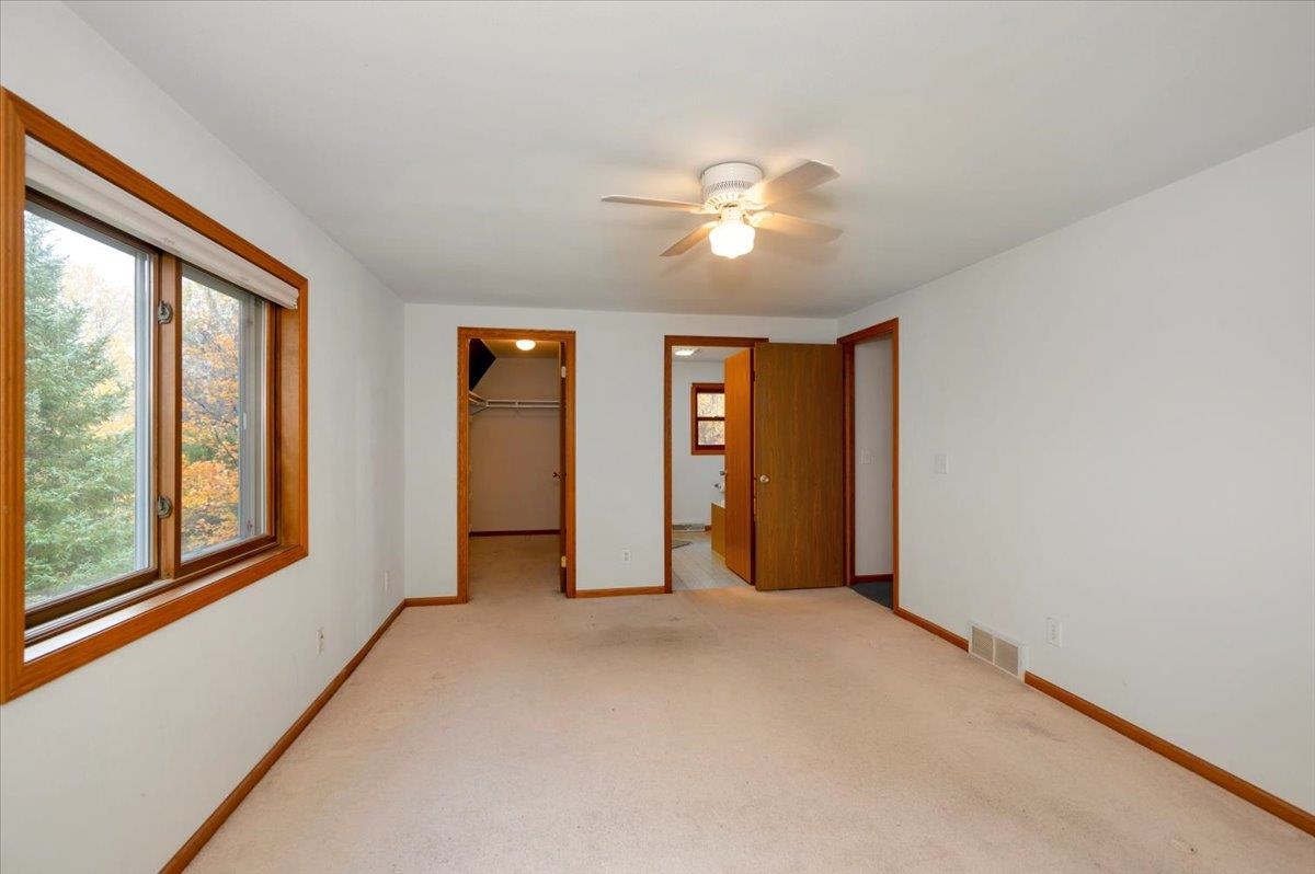 6373 Maple Grove Road Cloquet, MN 55720 - Photo 16 of 42 Unfurnished bedroom with carpet flooring, a walk in closet, connected bathroom, and ceiling fan