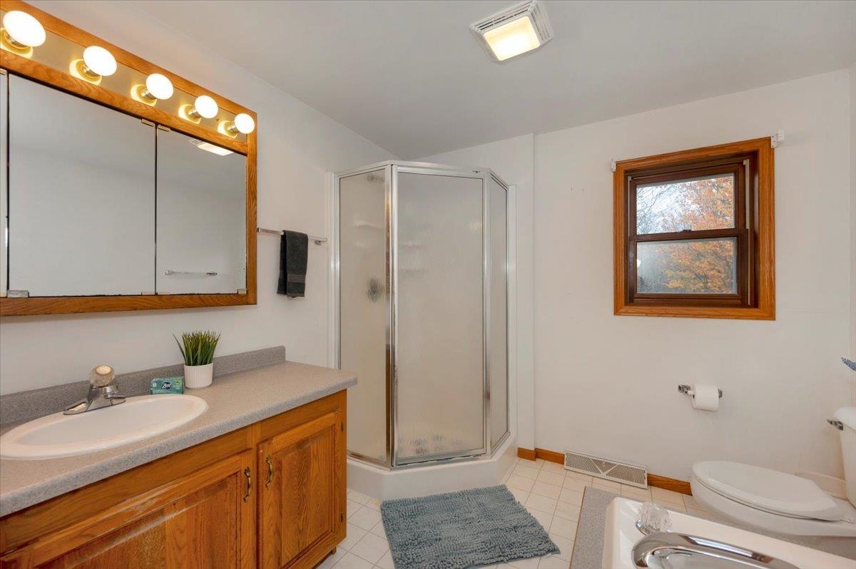 6373 Maple Grove Road Cloquet, MN 55720 - Photo 17 of 42 Bathroom featuring a stall shower, vanity, and light tile patterned flooring