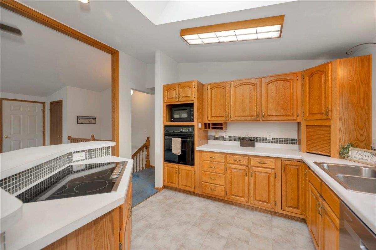 6373 Maple Grove Road Cloquet, MN 55720 - Photo 9 of 42 Kitchen with lofted ceiling, black appliances, light countertops, light flooring, and brown cabinets