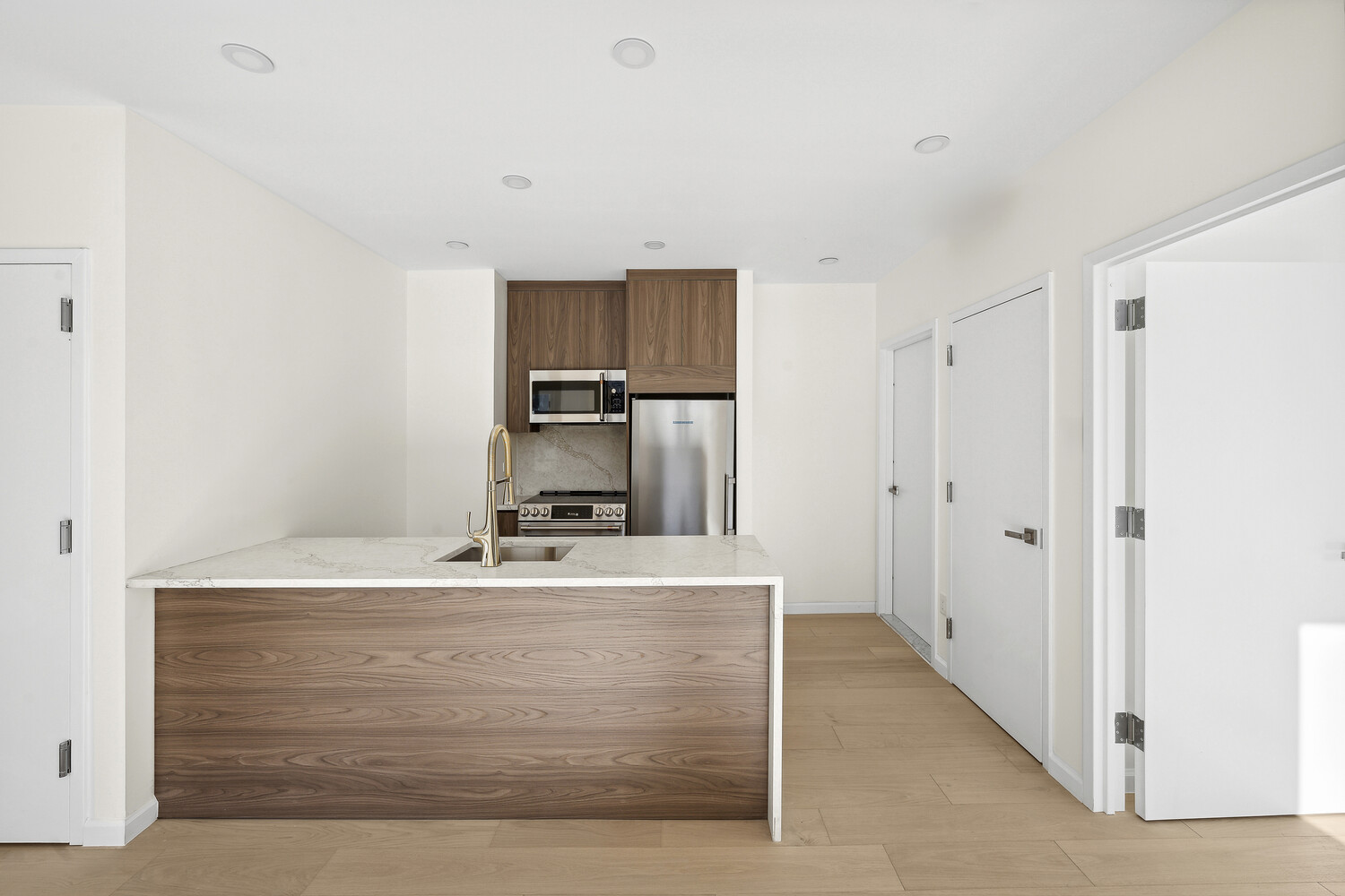 229 Withers Street, Unit 3A Brooklyn, NY 11211 - Photo 4 of 7 a room with kitchen island a sink a stove and a refrigerator with wooden floor