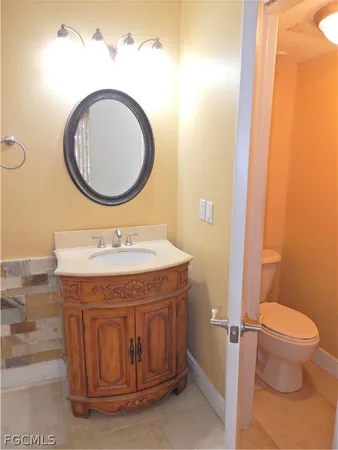 a bathroom with a granite countertop toilet a sink and a mirror