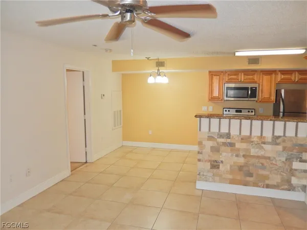 a view of a refrigerator in kitchen and an empty room