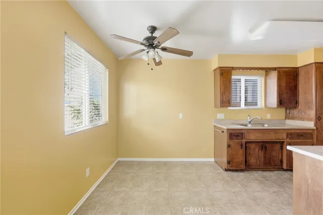 a view of an empty room with window and a kitchen