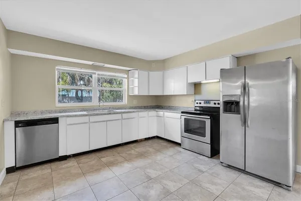 a kitchen with granite countertop white cabinets and window
