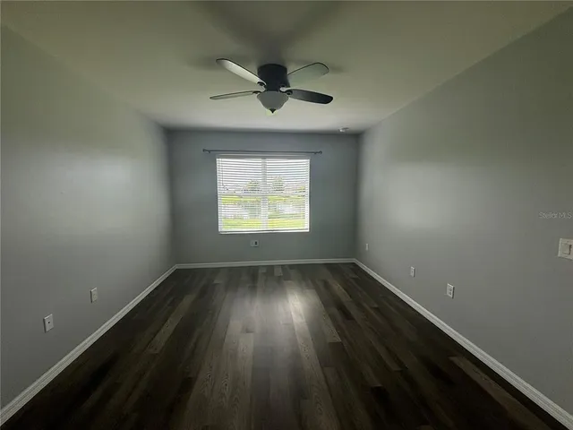 an empty room with wooden floor chandelier and windows