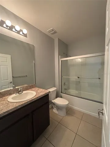 a bathroom with a granite countertop sink a toilet a mirror and shower
