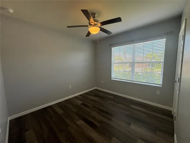 a view of an empty room with window and ceiling fan