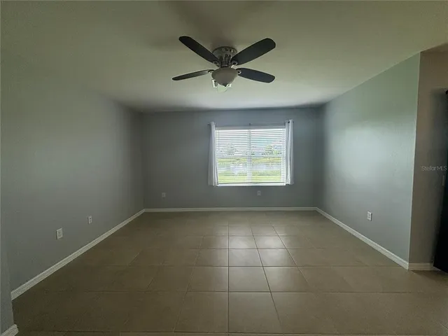 an empty room with ceiling fan and windows