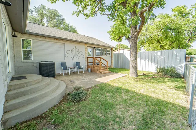 a view of a house with a yard and a large tree