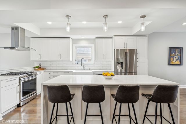 a kitchen with stainless steel appliances a stove a refrigerator a sink a dining table and chairs