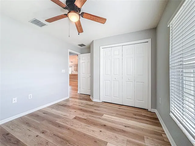 an empty room with wooden floor fan and windows