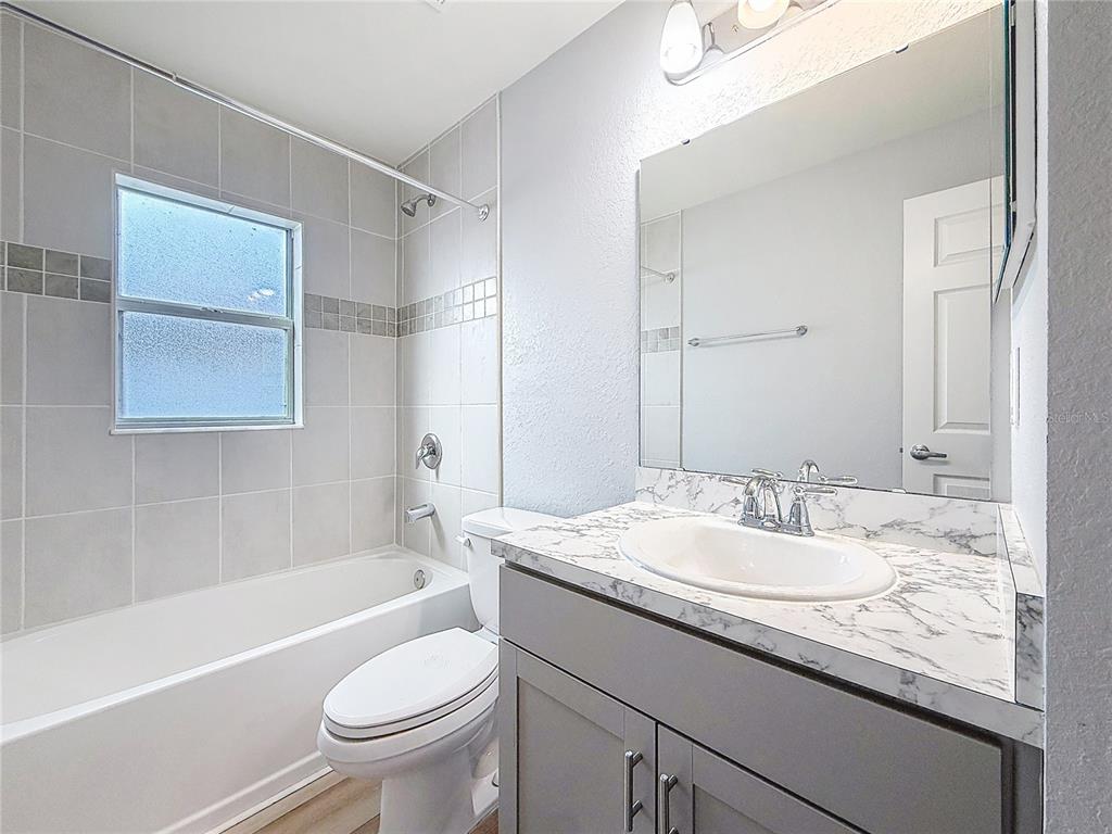 6945 Gideon Circle Zephyrhills, FL 33541 - Photo 14 of 45 a bathroom with a granite countertop sink toilet mirror and bathtub