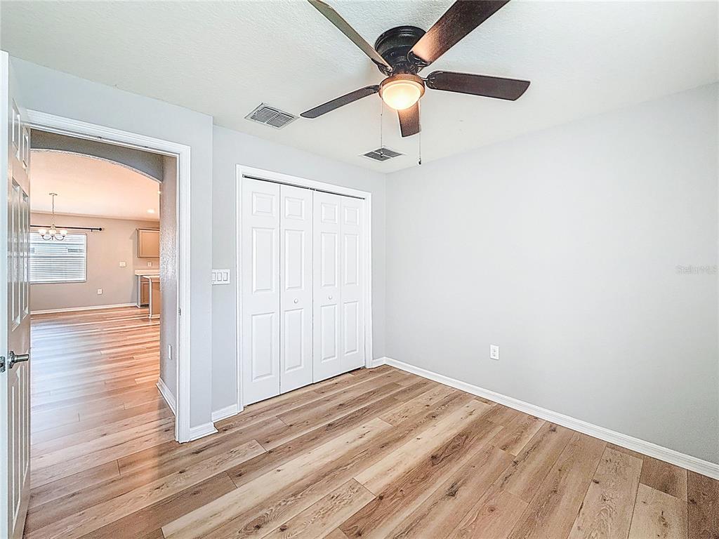 6945 Gideon Circle Zephyrhills, FL 33541 - Photo 27 of 45 an empty room with wooden floor fan and windows