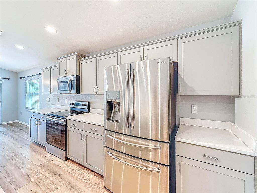 6945 Gideon Circle Zephyrhills, FL 33541 - Photo 6 of 45 a kitchen with stainless steel appliances a refrigerator sink and microwave