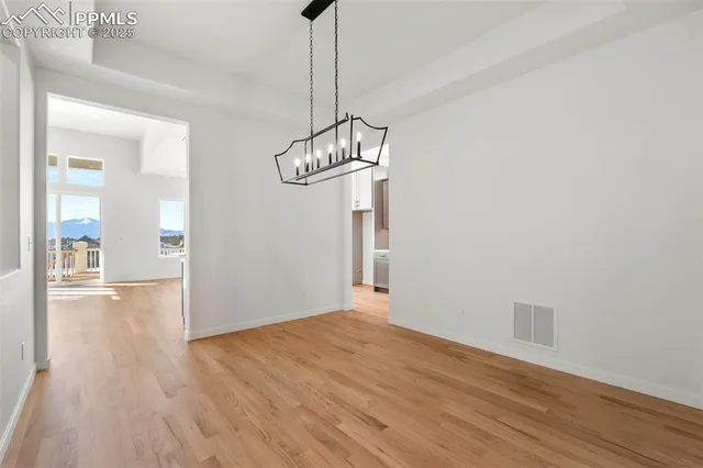 a view of an empty room with wooden floor and a chandelier