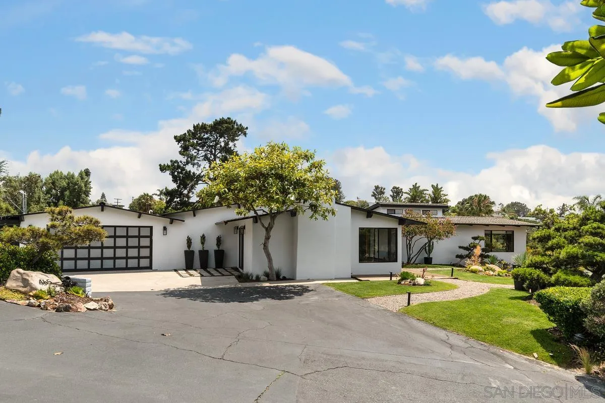 a front view of a house with a garden and mountain view