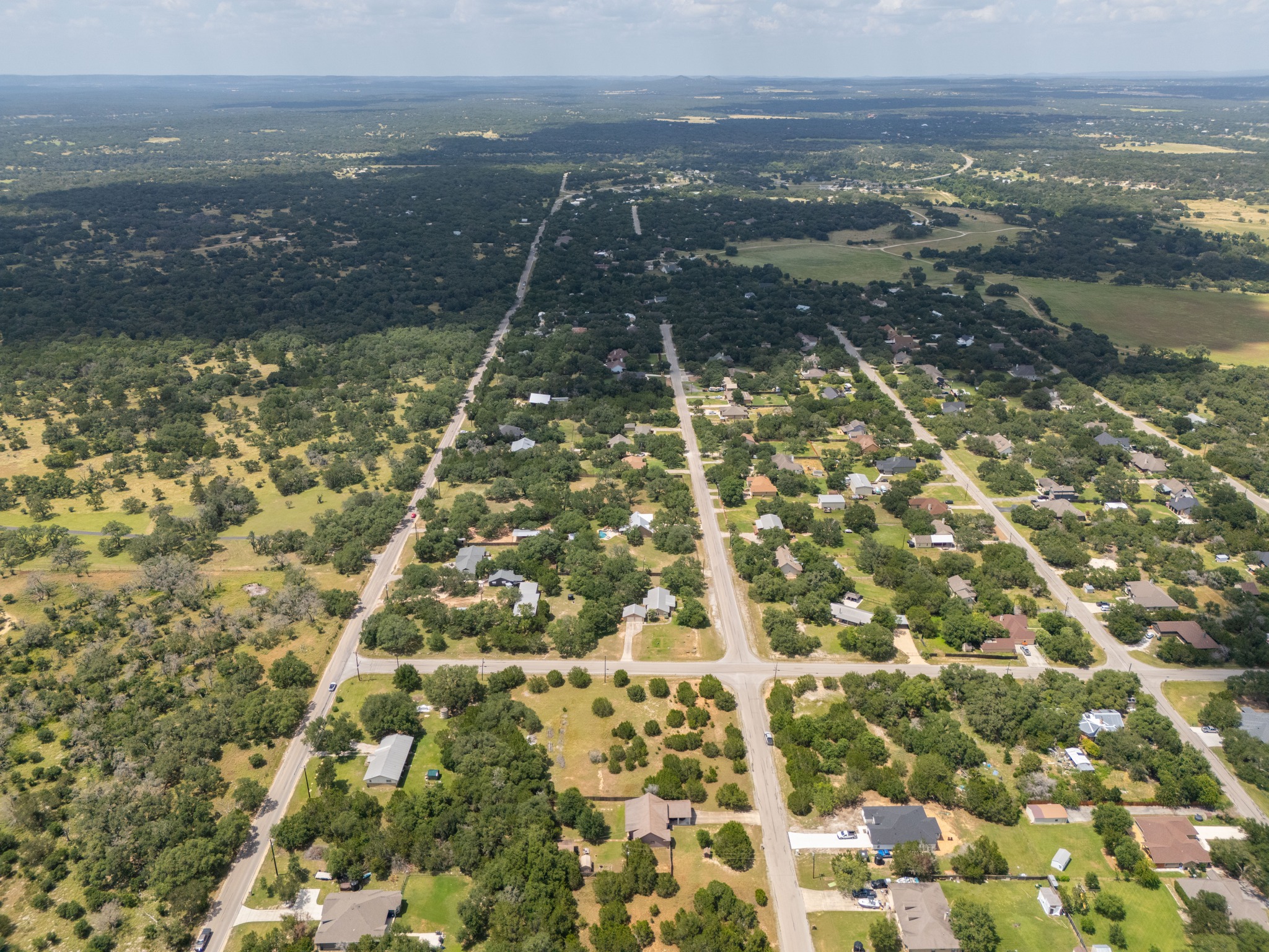 1170 Misty Lane Spring Branch, TX 78070 - Photo 7 of 24 An aerial perspective reveals a vast, tree-filled neighborhood with scattered homes, extending into distant natural landscapes.