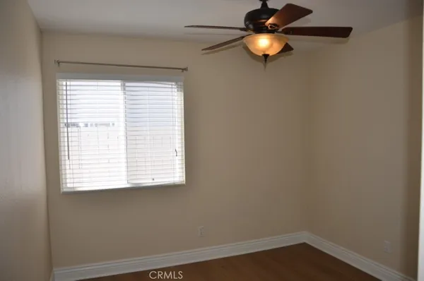 a view of an empty room with window and chandelier fan
