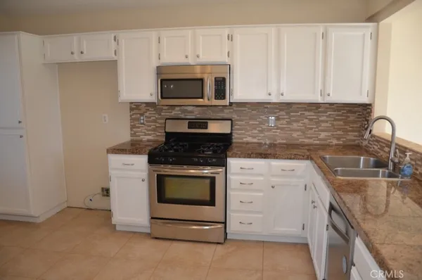 a kitchen with granite countertop white cabinets stainless steel appliances and a sink