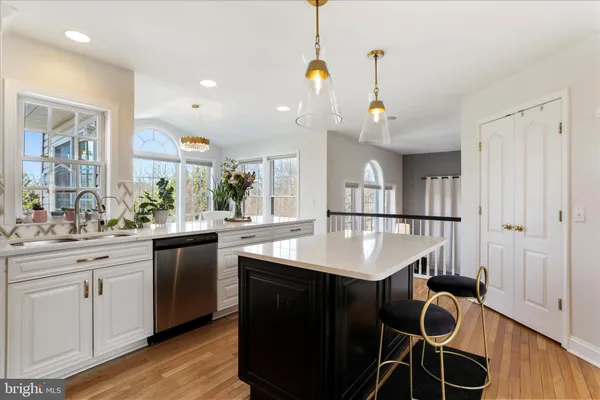 a kitchen with kitchen island granite countertop a stove a oven a dining table and chairs with wooden floor